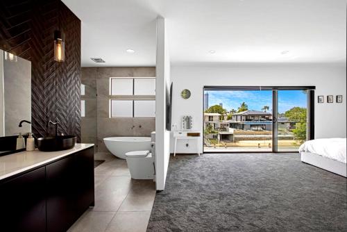 baño con bañera, cama y lavamanos en Urban Hideaway Pet Friendly, en Gold Coast