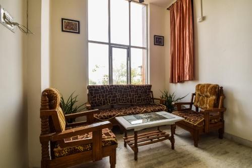 a living room with a couch and two chairs at Hotel O Kanchan Residency in Kota