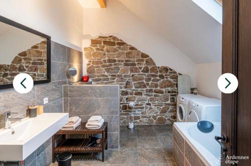 y baño con paredes de piedra, lavabo y lavadora. en L'Hoursinne, en Érezée