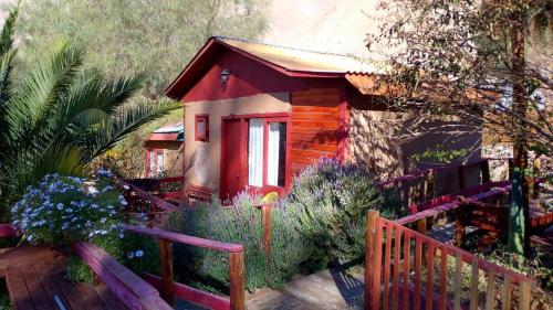 a small red cabin with a wooden fence at Lodge Gabriela Mistral in Pisco Elqui