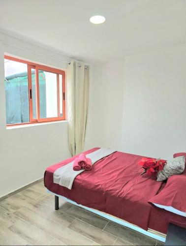 a bedroom with a bed with red sheets and a window at La Casita de Beni Valencia in Valencia