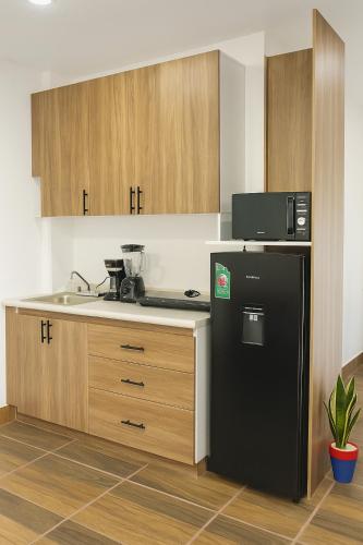 a kitchen with a black refrigerator and wooden cabinets at Condominio Alegre Amanecer in Santa Cruz Huatulco