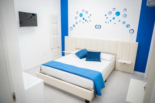 Schlafzimmer mit einem weißen Bett mit blauen Akzenten in der Unterkunft Le Cromie di Amelie in Ceglie Messapica