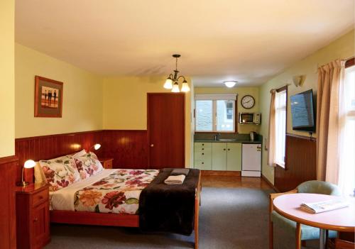 a bedroom with a bed and a table and a kitchen at Queenstown Holiday Park Creeksyde in Queenstown