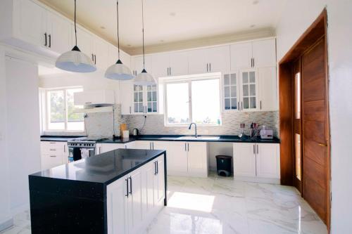 a kitchen with white cabinets and a black counter top at Elegant Lakeside Villa in Kibuye, Rwanda in Mwendo