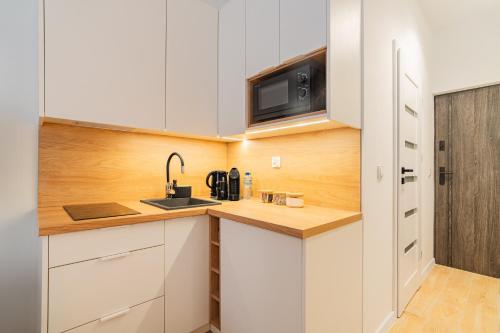 eine Küche mit weißen Schränken und einer Spüle in der Unterkunft Raciborska Old Town in Gliwice