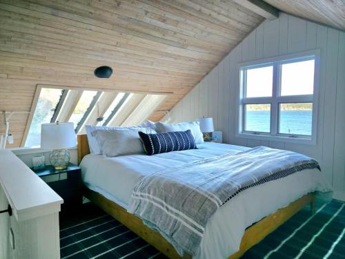 ein Schlafzimmer mit einem Bett und einem großen Fenster in der Unterkunft Beachfront cabin, dock, water views in Point White