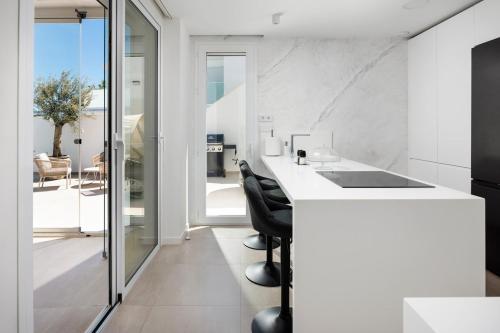 eine Küche mit einer weißen Theke und schwarzen Stühlen in der Unterkunft Casa Blanca in Torre del Mar