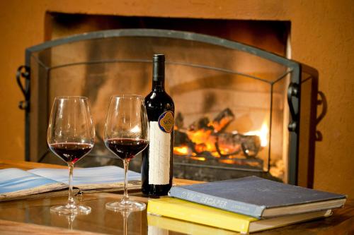 a bottle of wine and two glasses on a table with a fireplace at Pousada do Quilombo in São Bento do Sapucaí