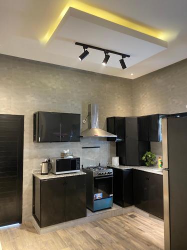 a kitchen with black cabinets and a stove at لامور فيلا in Sohar