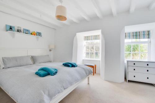 ein weißes Schlafzimmer mit einem Bett mit blauen Kissen darauf in der Unterkunft Stepaside Cottage in Fowey