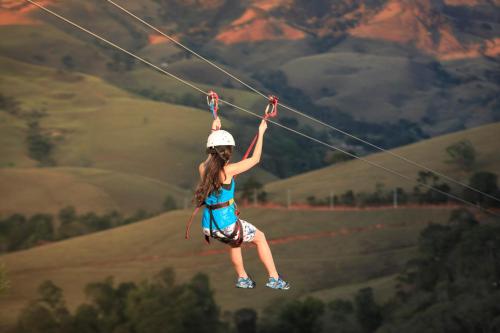 a girl on a zip line in the mountains at Pousada do Quilombo in São Bento do Sapucaí
