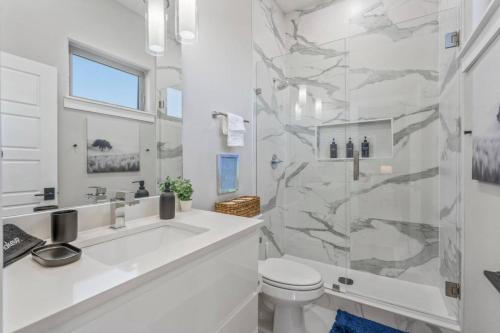 a white bathroom with a shower and a toilet at Elegant 2BD Townhome 7TH St Walkable in Fort Worth