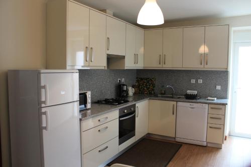 a kitchen with white cabinets and a white refrigerator at A casa do meu Avô in Viana do Castelo