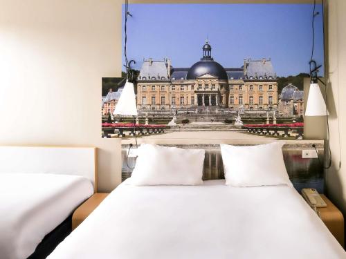 エムランビルにあるibis Paris Marne la Vallee Emerainvilleのベッドルーム1室(ベッド2台付)が備わる大きな建物です。