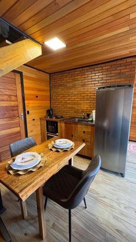 a kitchen with a wooden table and a refrigerator at Vale Encantado Alfredo Wagner in Barracão