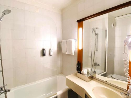 een badkamer met een bad, een wastafel en een spiegel bij Hotel ibis Porto Sul Europarque in Santa Maria da Feira