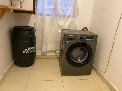 uma máquina de lavar roupa e uma lata de lixo num quarto em Upendocozy villa em Praia de Diani