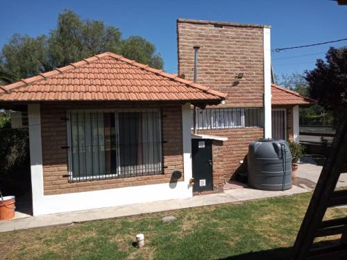 una piccola casa di mattoni con un bidone della spazzatura nel cortile di Divina Providencia a Merlo