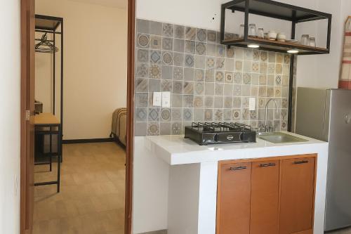 a kitchen with a counter and a sink and a refrigerator at Casa Layu Oaxaca in Oaxaca City