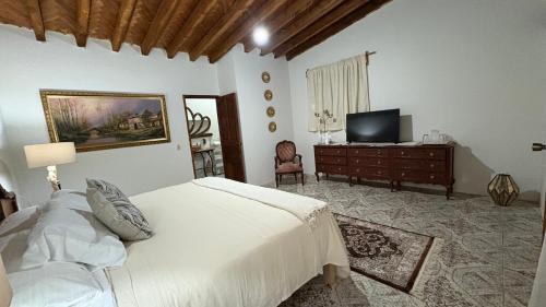 a bedroom with a white bed and a television at hotel gardenias in Pátzcuaro
