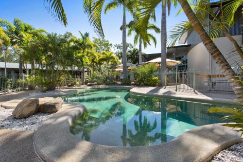 a swimming pool with palm trees and a building at Capricorn Motel & Conference Centre in Rockhampton