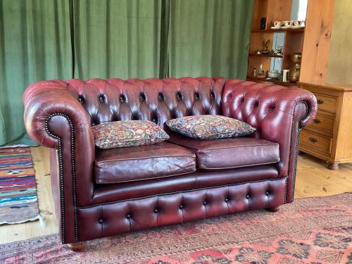 a brown leather couch with two pillows on it at Secret Forest Cabin in Jackeys Marsh