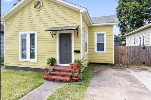 a yellow house with a door and some potted plants at Modern Cajun Retreat Near Downtown in Lafayette