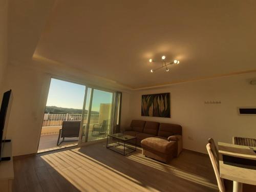 een woonkamer met een bank en een tafel bij Sunsets Duplex Penthouse Gozo in Kerċem