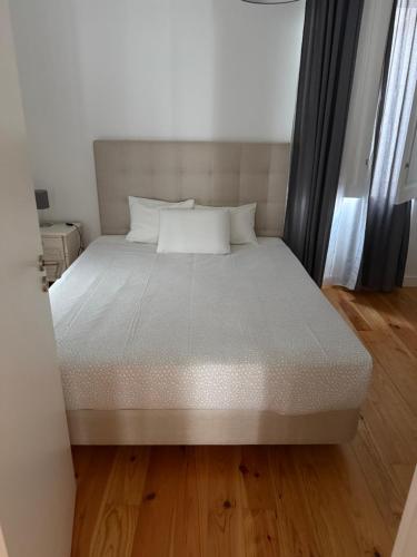 Una cama grande en una habitación con suelo de madera. en Pátio Prior do Crato 4, en Almada