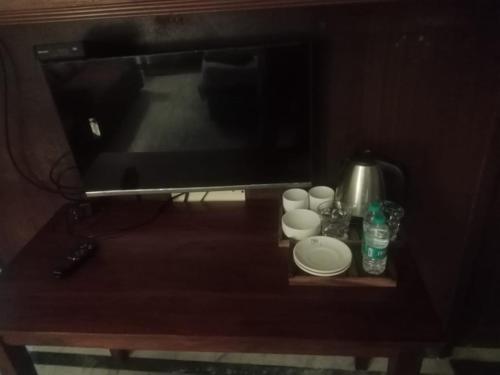 Una mesa con platos y tazas y un televisor. en Aathira urbanite, en Chennai