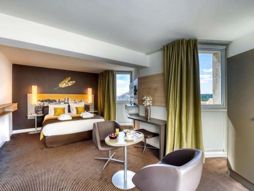 a hotel room with a bed and a table at Mercure Avignon Centre Palais des Papes in Avignon