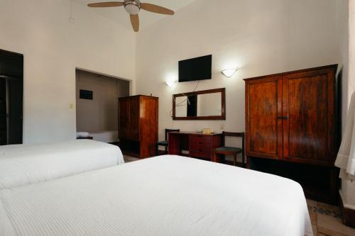 a bedroom with two beds and a dresser and a tv at Hotel Nueva Antequera in Oaxaca City