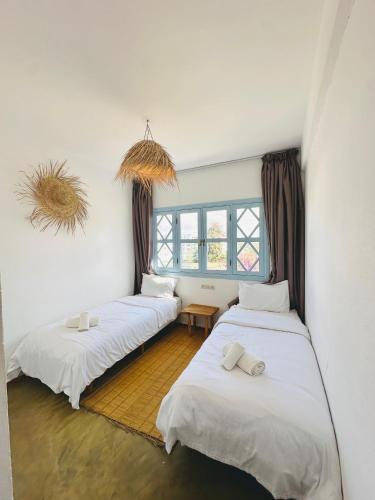 a room with three beds and a window at Appartement Les Vagues Vue sur Mer pour familles in Oualidia