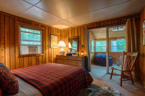 Un dormitorio con una cama y una silla y ventanas. en Gorgeous Chalet in the Poconos w/ Hot Tub!, en Locust Lakes Village