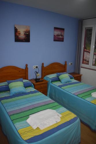 2 Betten in einem Schlafzimmer mit blauen Wänden in der Unterkunft Pensión 15 de Mayo in La Pola de Gordón