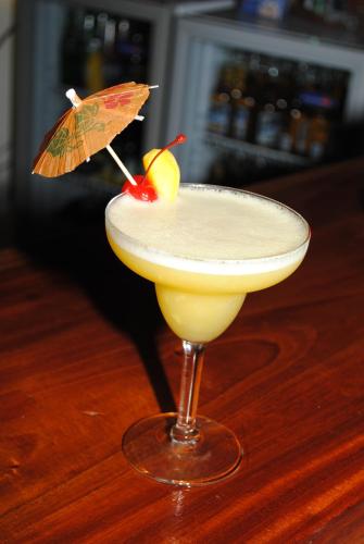 a cocktail with an umbrella on a wooden table at Captain's Lodge and Bar in Panglao