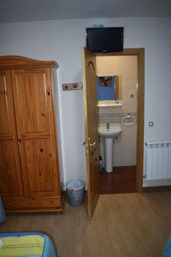 ein Bad mit einem Waschbecken, einem WC und einer Tür in der Unterkunft Pensión 15 de Mayo in La Pola de Gordón