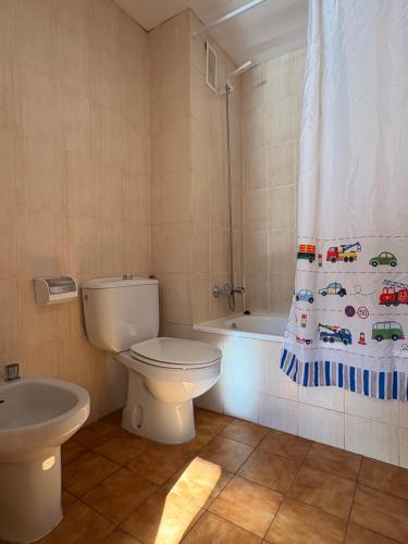 a bathroom with a toilet and a shower curtain at Tu rincón- Planta baja con jardín y parking - Dellui 2 in Pla de l'Ermita