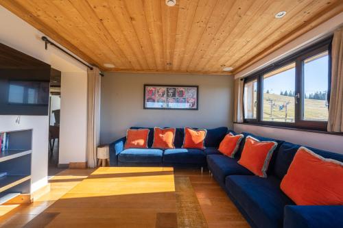a living room with a blue couch with orange pillows at Le Flocon d'Argent in Les Gets