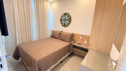 a small bedroom with a bed and a clock on the wall at Flat 1 quarto Beach Porto - By Duuna Temporada in Porto De Galinhas