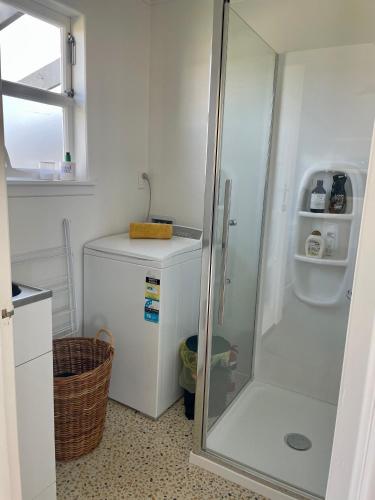 a bathroom with a shower and a white refrigerator at Epic Beachfront Bure - Taipa in Taipa