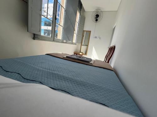 a bedroom with a bed with a blue blanket and a window at Rota BH Hostel in Belo Horizonte