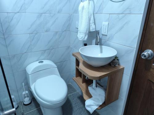 um banheiro com um vaso sanitário branco e uma pia em Hotel Alma Verde em Chiquinquirá