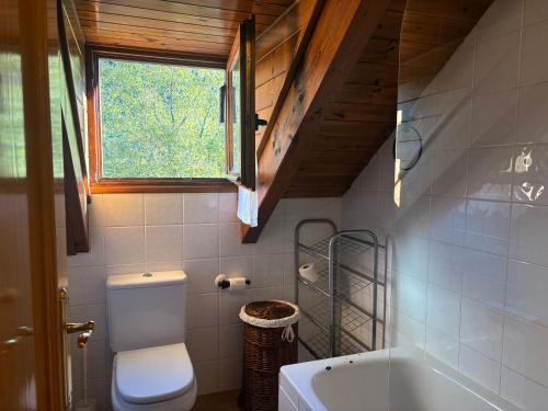 baño con aseo, bañera y ventana en Cocina moderna, bajo cubierta rústico- Comodidad máxima - Erta 3, en Pla de l'Ermita