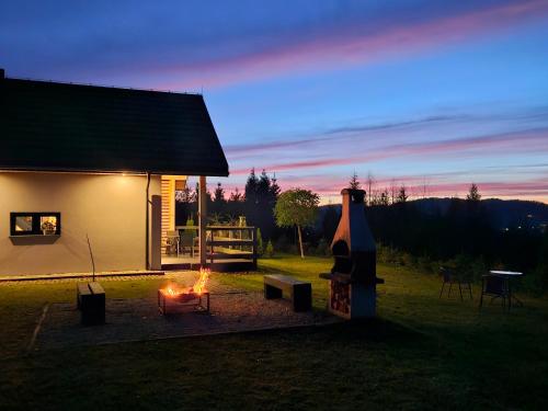 a fire pit next to a building with a house at Bieszczadzka Pauza in Polańczyk