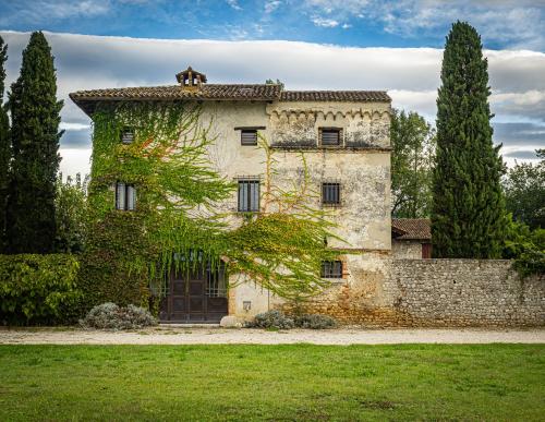 ein altes Steingebäude mit Bäumen davor in der Unterkunft La Torre della Casaforte Bergum alle porte di Cividale del Friuli in Cividale del Friuli