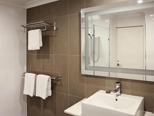 Un baño con lavabo, espejo y toallas. en Novotel Vines Resort Swan Valley, en Upper Swan