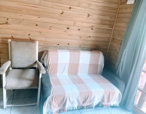 a small bedroom with a bed and a chair at Bombinhas, Casa mobiliada 1 quarto in Bombinhas