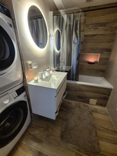 a bathroom with a sink and a shower and a washing machine at Apartmán LUX Lučenec in Lučenec